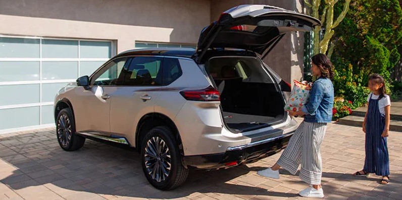 A photo of a woman placing items in to the back of a new 2025 Nissan Rogue.