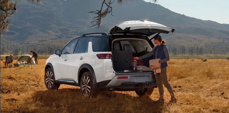 A woman loading camping gear in to the back of a 2025 Nissan Pathfinder.